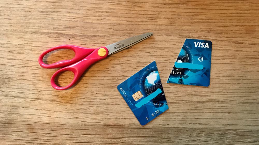 Een creditcard van Visa in twee stukken geknipt, de schaar ligt er nog naast