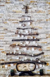Een kerstboom gemaakt van takken die bij elkaar zijn gebonden met touw, aan de takken hangen kerstballen en andere decoraties
