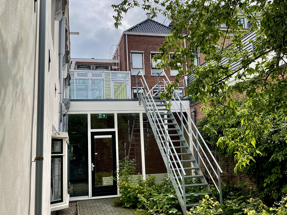 Een muur met een deur, oftewel het einde van het steegje (een brandtrap voert naar een plat dak)