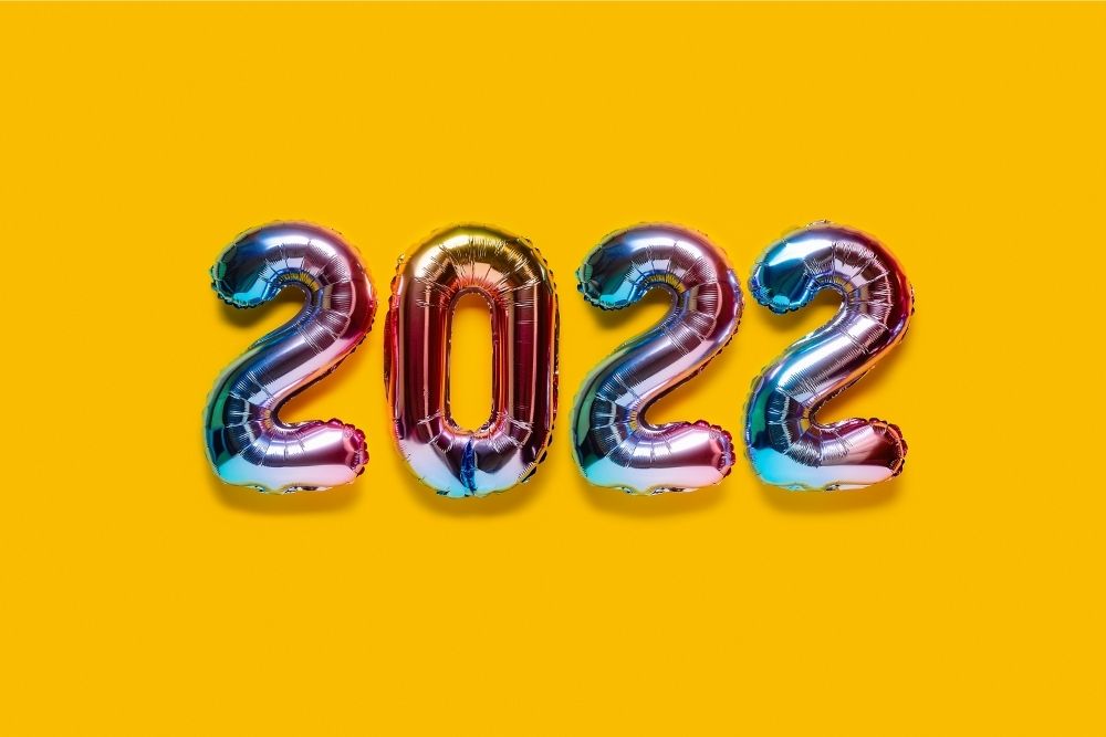 Het getal 2022 in vier glimmende ballonnen op een knalgele achtergrond (vergeet goede voornemens, ze werken vaak niet goed)